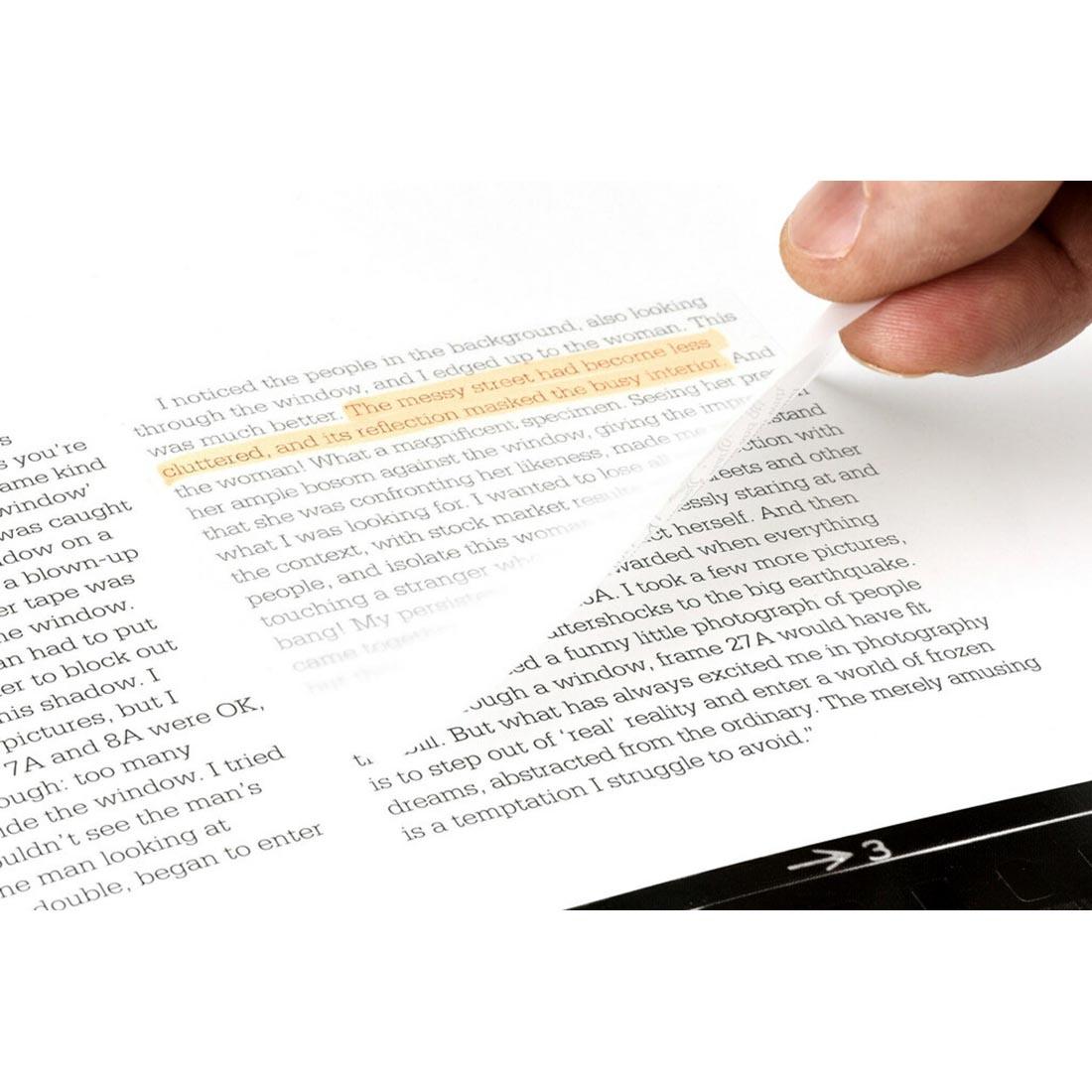 fingers lifting a Transparent Post-It Note off of a sheet of text