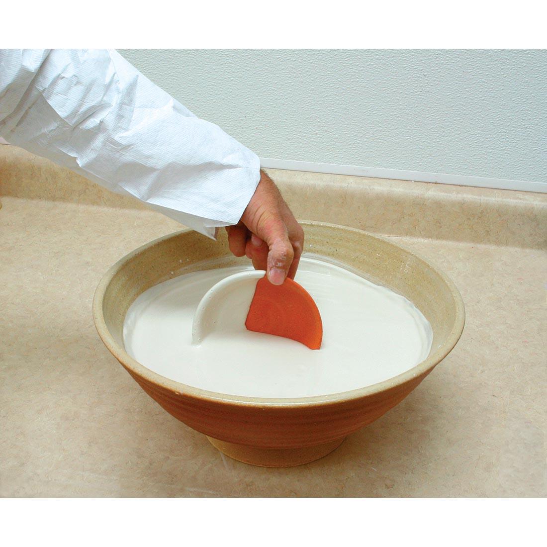 pottery being dipped into a bowl of AMACO Clear Low Fire Dipping Glaze
