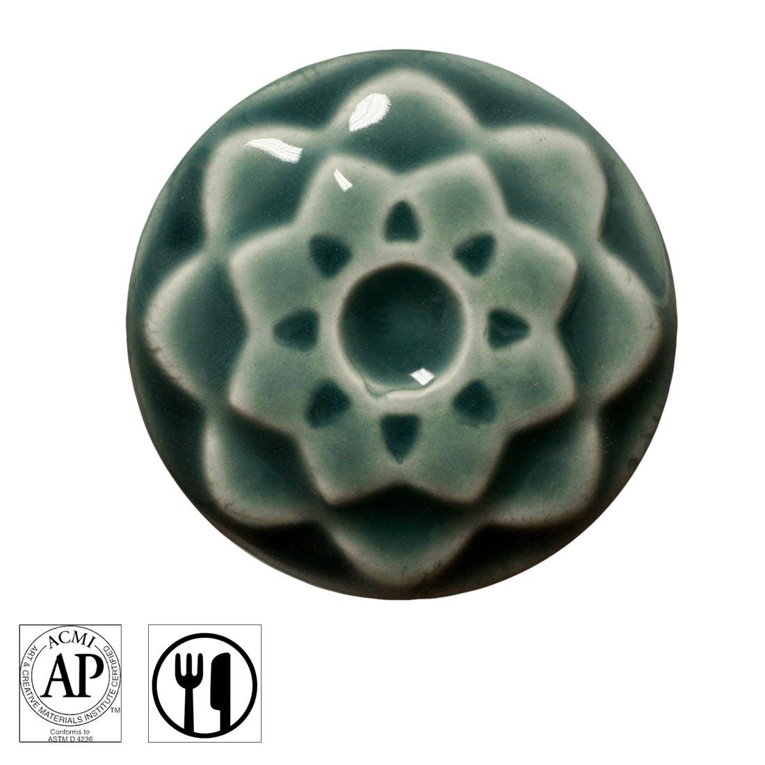 clay chip with Fog AMACO Celadon High Fire Transparent Gloss Glaze applied; symbols for AP Seal and food safe