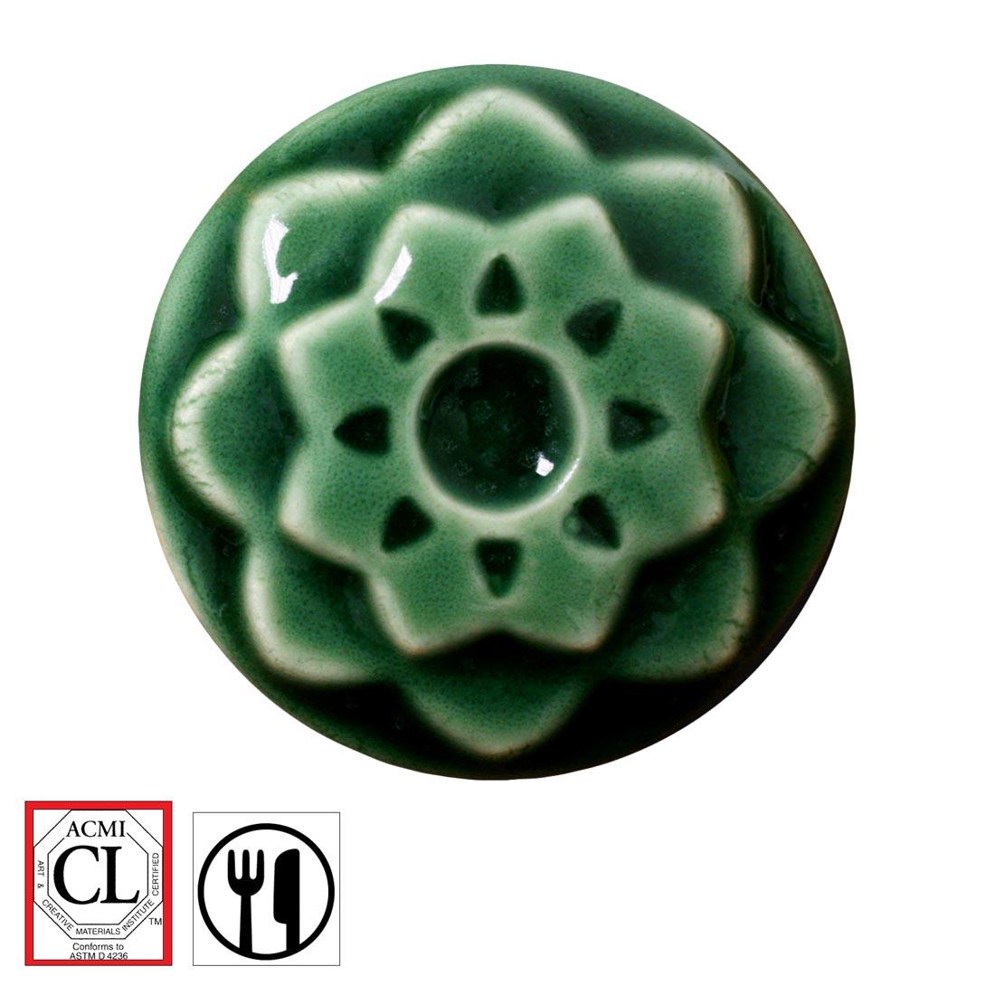 clay chip with Jade AMACO Celadon High Fire Transparent Gloss Glaze applied; symbols for Cautionary Label and food safe