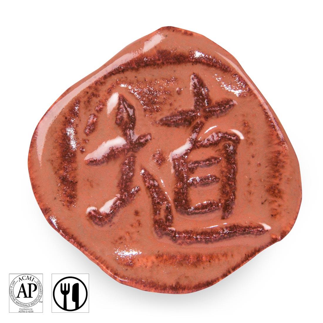 clay chip with Hibiscus Gloss AMACO Shino High Fire Glaze applied; symbols for AP Seal and food safe