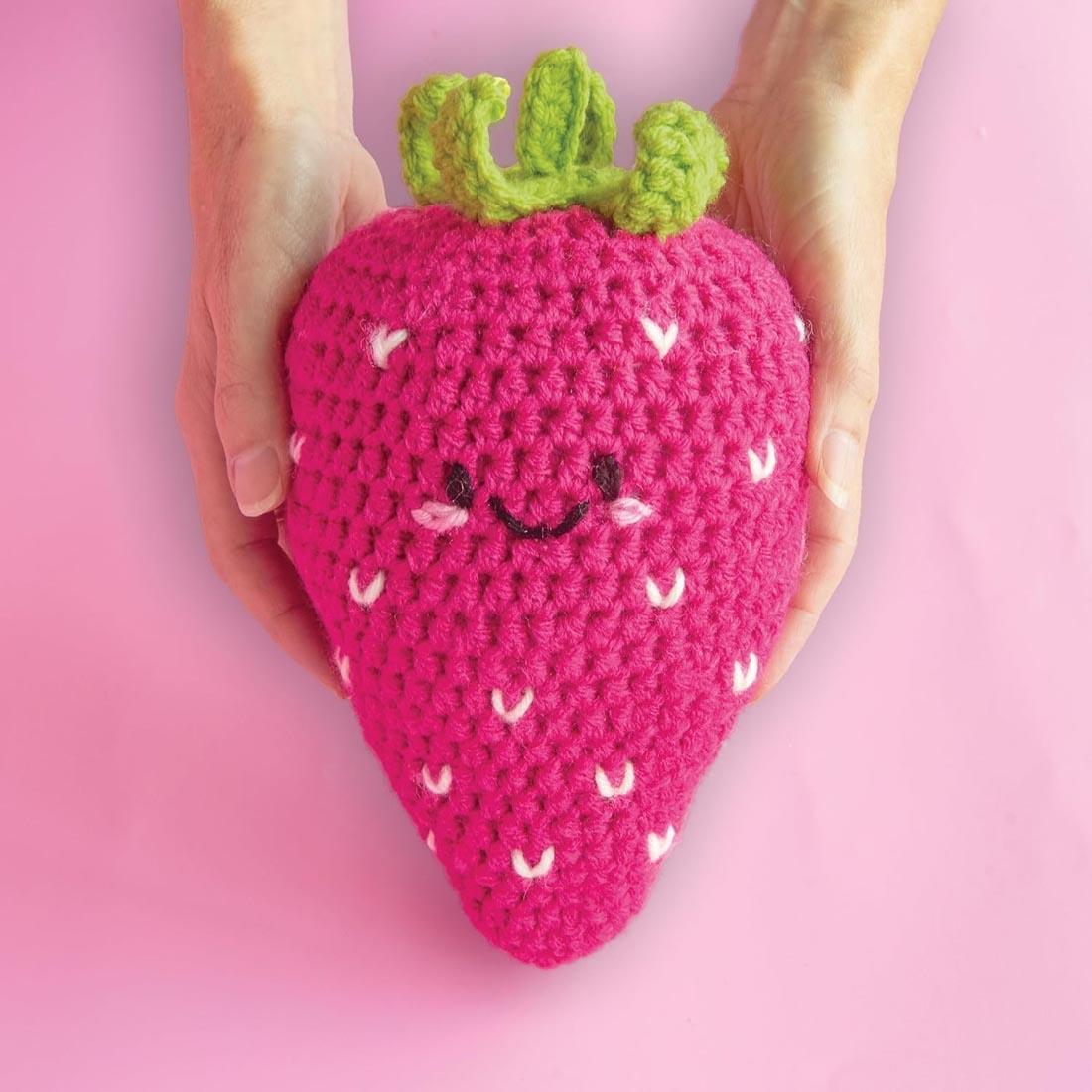hands holding an example strawberry made with the Learn To Crochet Avocado and Strawberry Kit