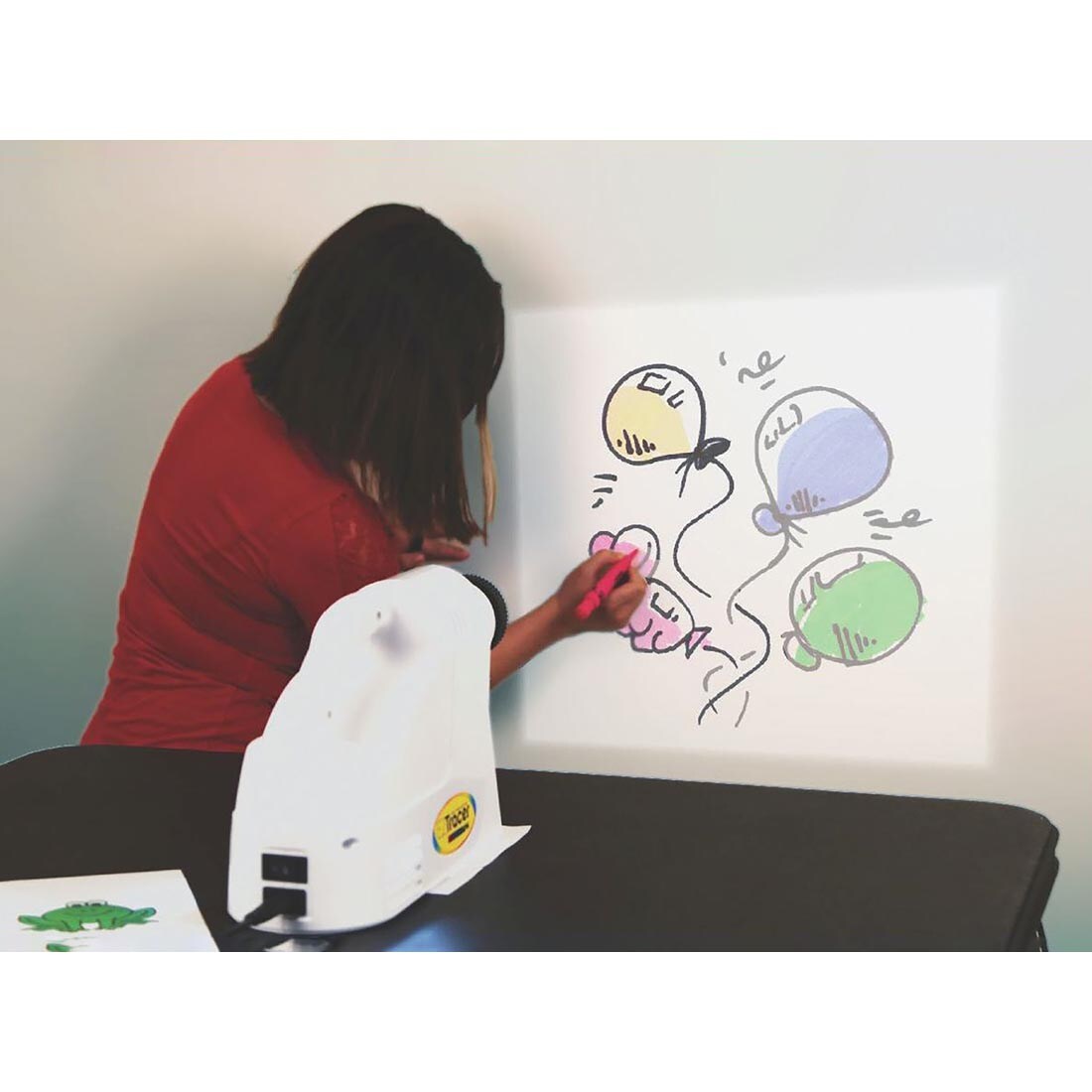 Person coloring an image projected on the wall by the Artograph EZ Tracer Projector