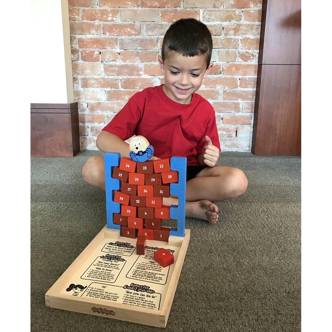 Child sitting on floor playing Don't Dump Dumpty Game by BeginAgain Toys