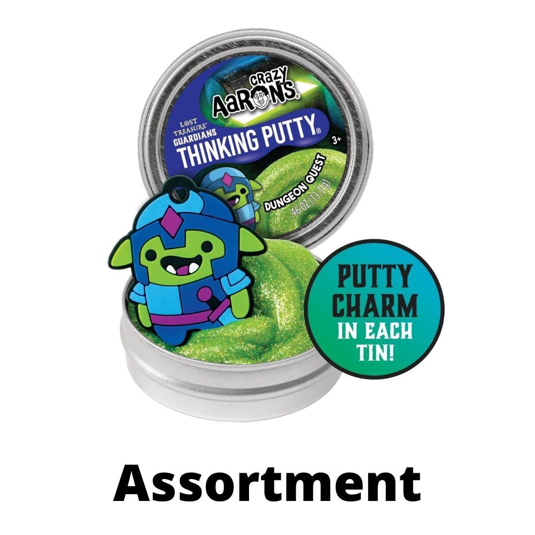Dungeon Quest Lost Treasure Guardians Mini Thinking Putty, shown with the lid off, and a mini charm, with the words "Putty charm in each tin" and "Assortment"