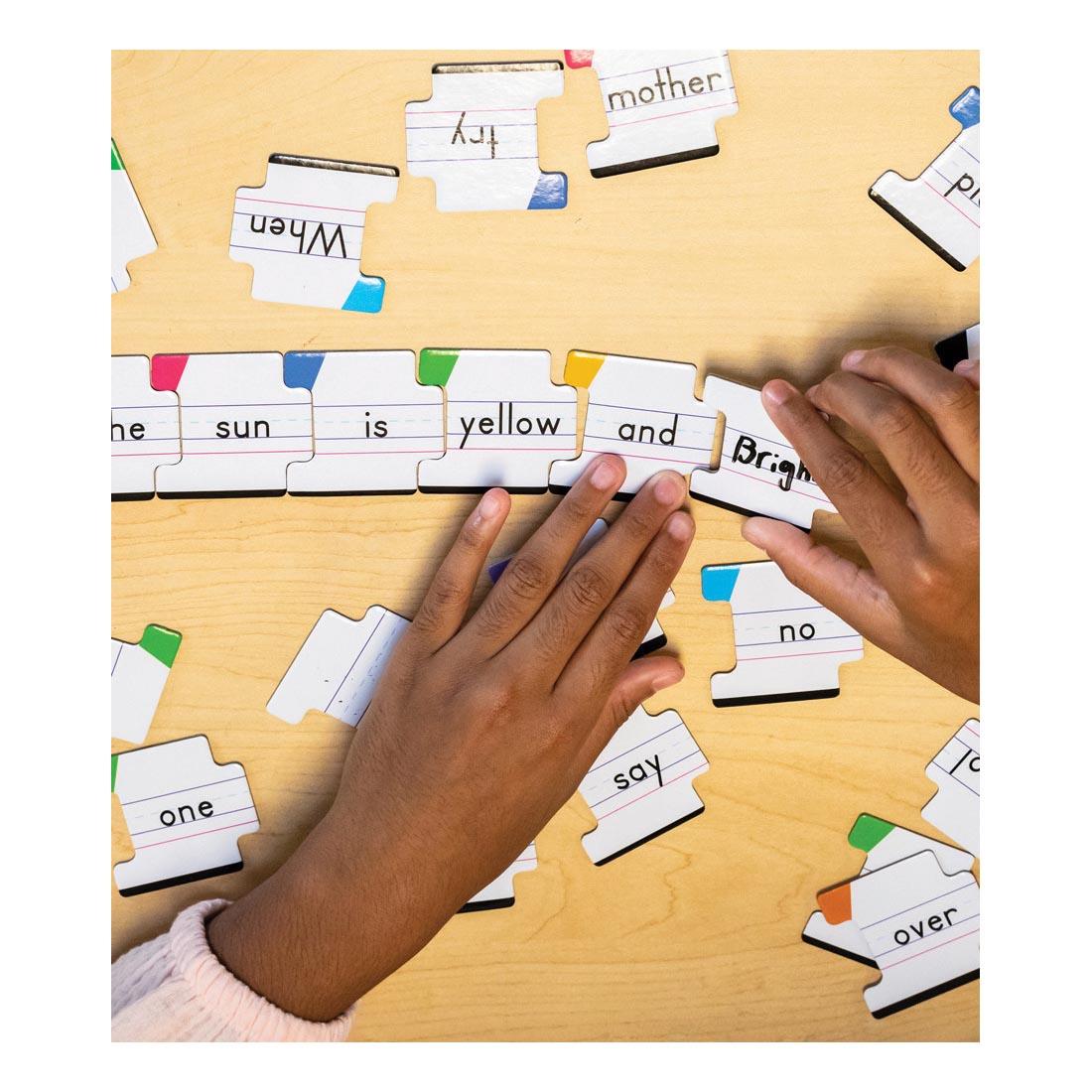 Hands putting together puzzle pieces in a sentence, from Big Box of Sentence Building by Carson Dellosa