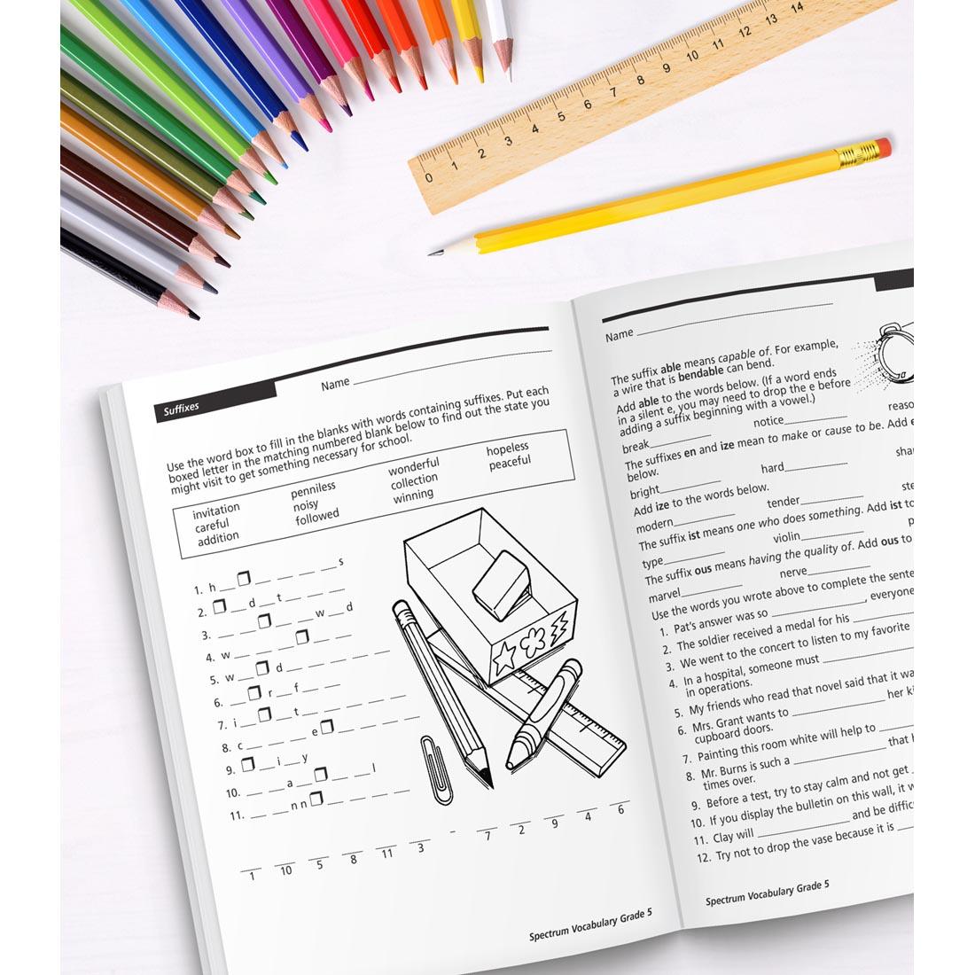 open book of Spectrum Vocabulary for Grade 5 along with colored pencils, a ruler and a pencil