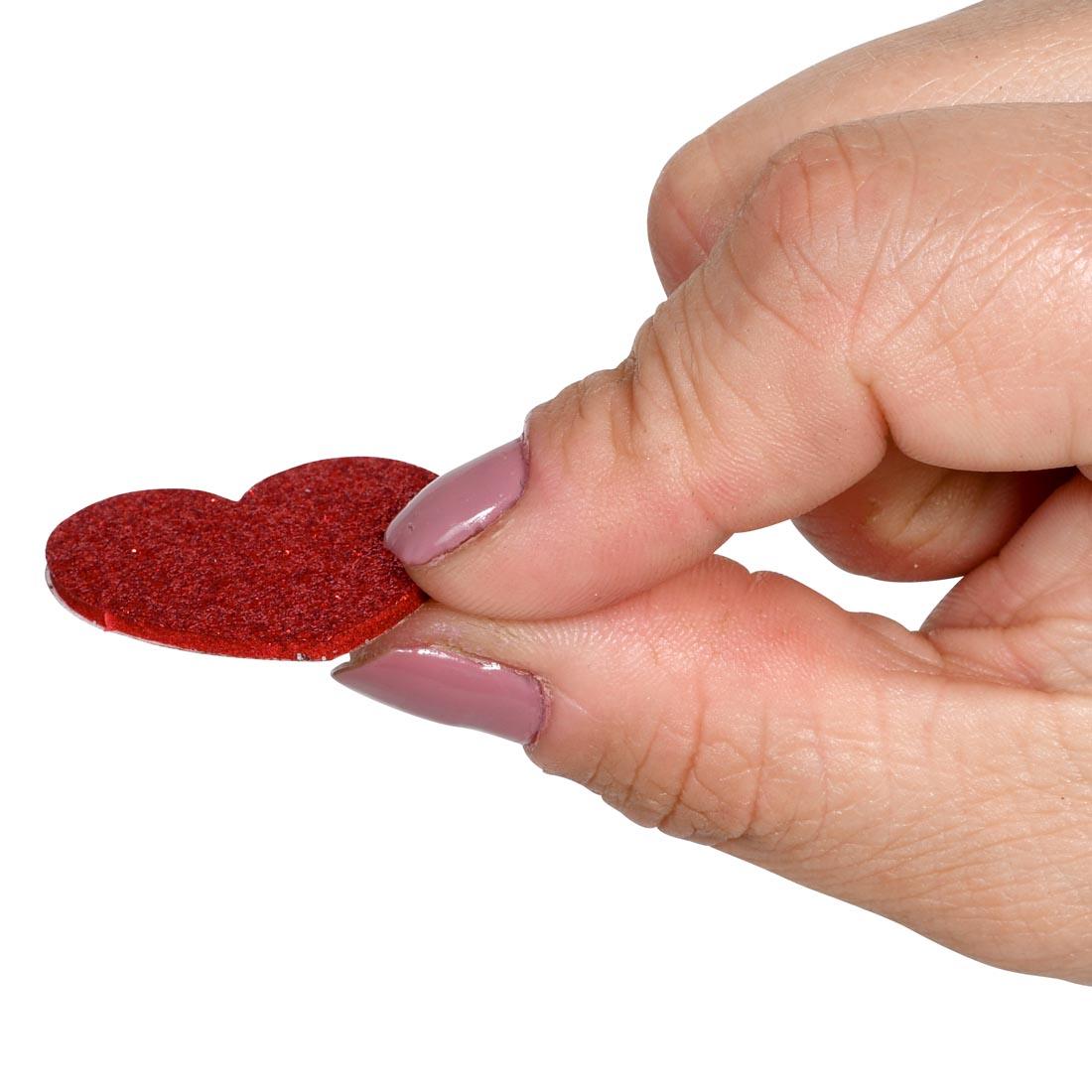 fingers holding a Ready 2 Learn Glitter Heart Foam Sticker