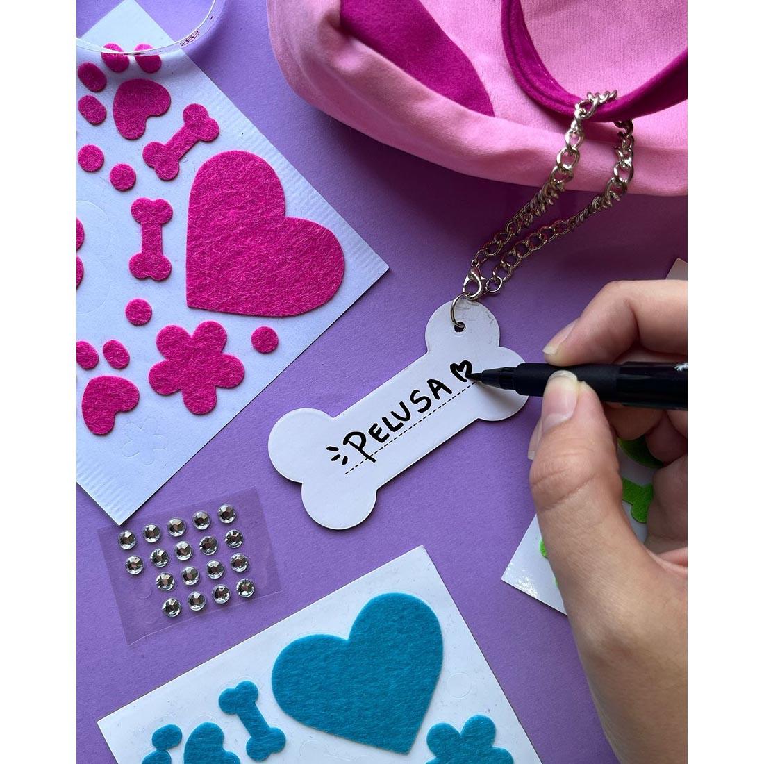 Hand writing dog name on bone charm, from Designer Doggie by Creativity For Kids craft kit