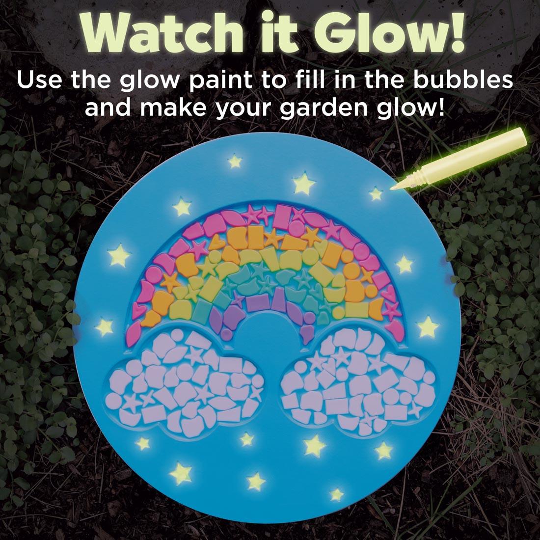 example of a completed Rainbow Garden Stone with text Watch it Glow! Use the glow paint to fill in the bubbles and make your garden glow!