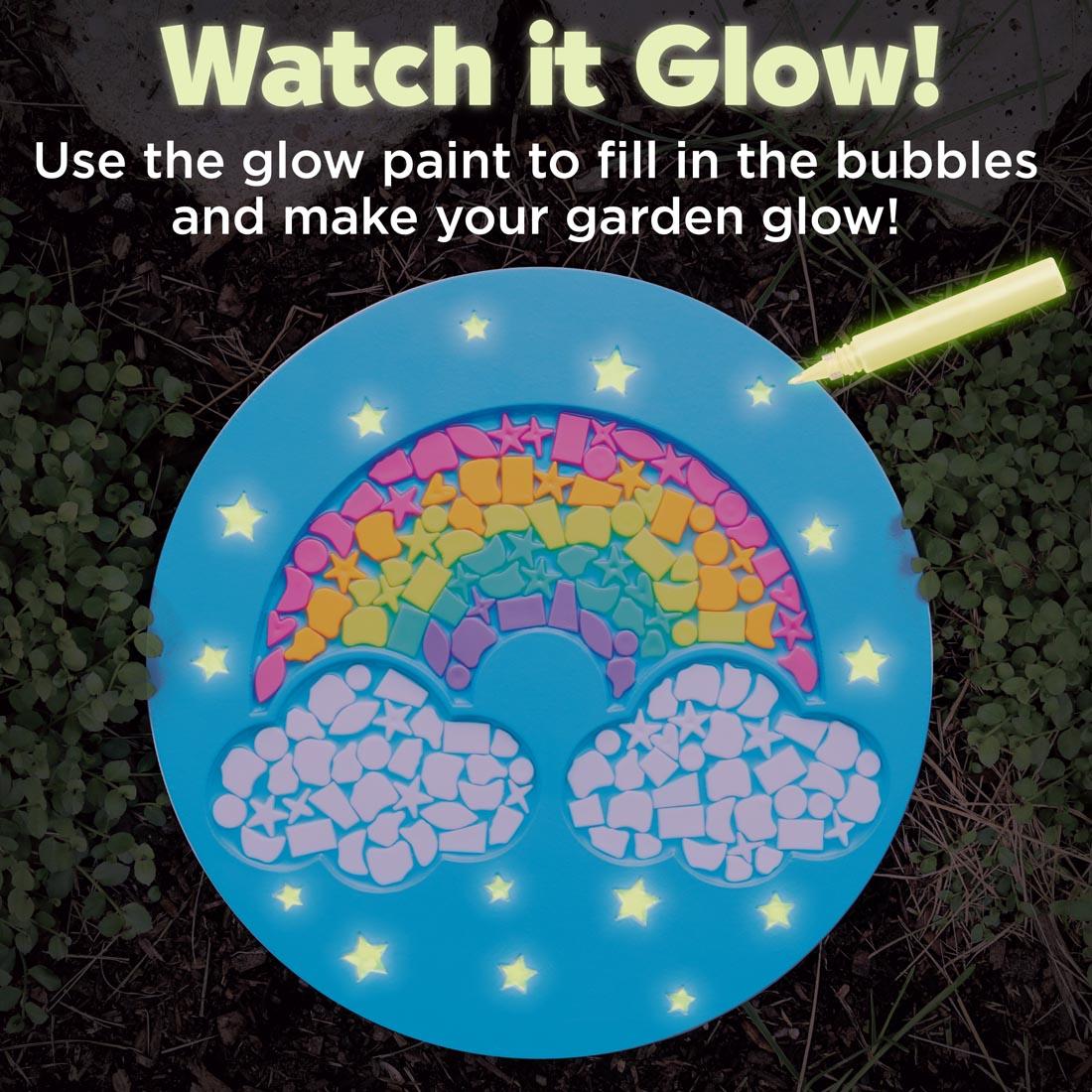 example of a completed Rainbow Garden Stone with text Watch it Glow! Use the glow paint to fill in the bubbles and make your garden glow!