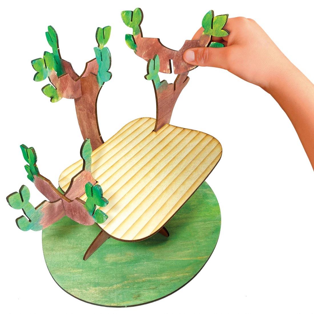 Build & Grow Tree House By Creativity For Kids, showing a hand attaching a piece of the tree house