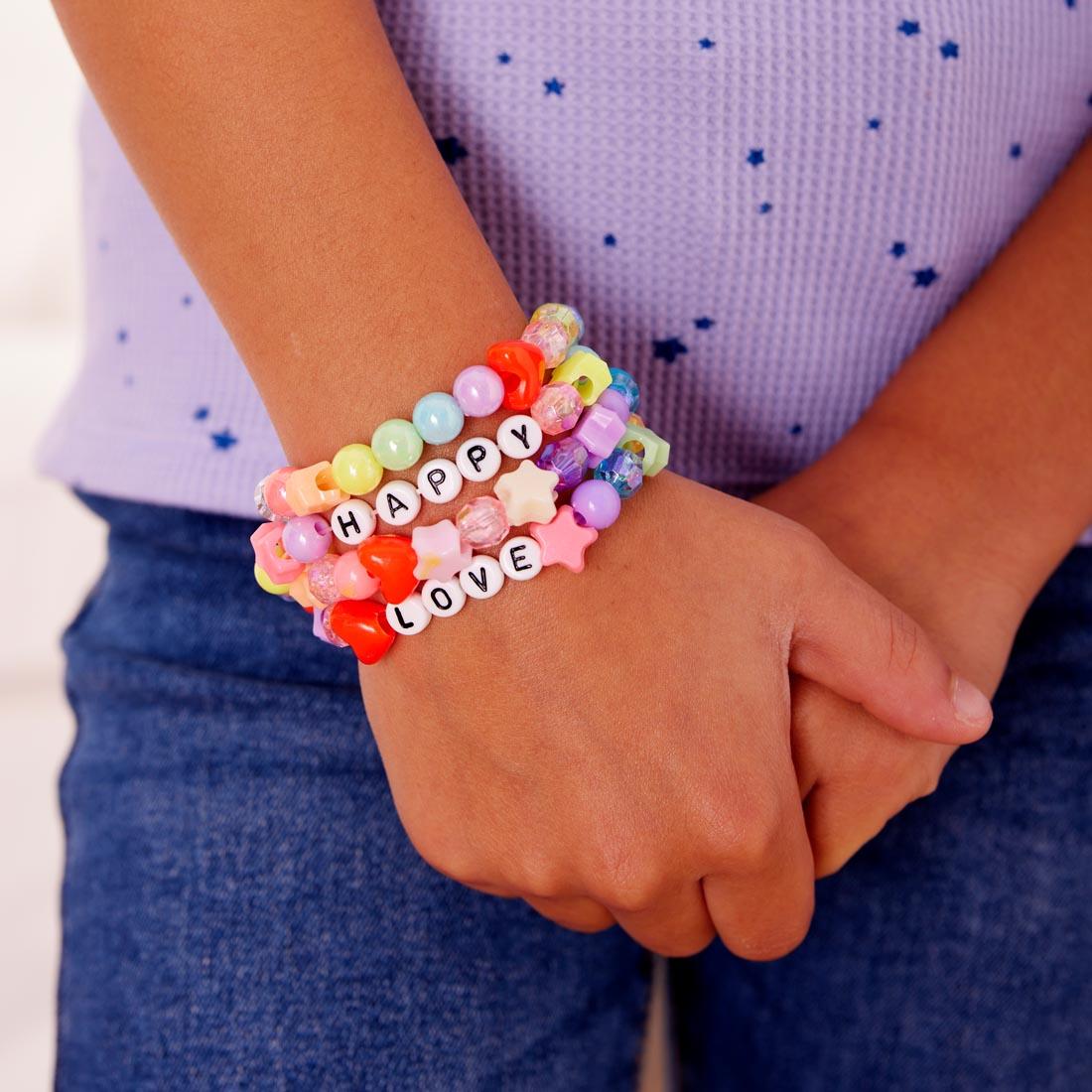 closeup of arm wearing 4 bracelets made with beads from Rainbow Bead Jewelry Jar By Creativity For Kids