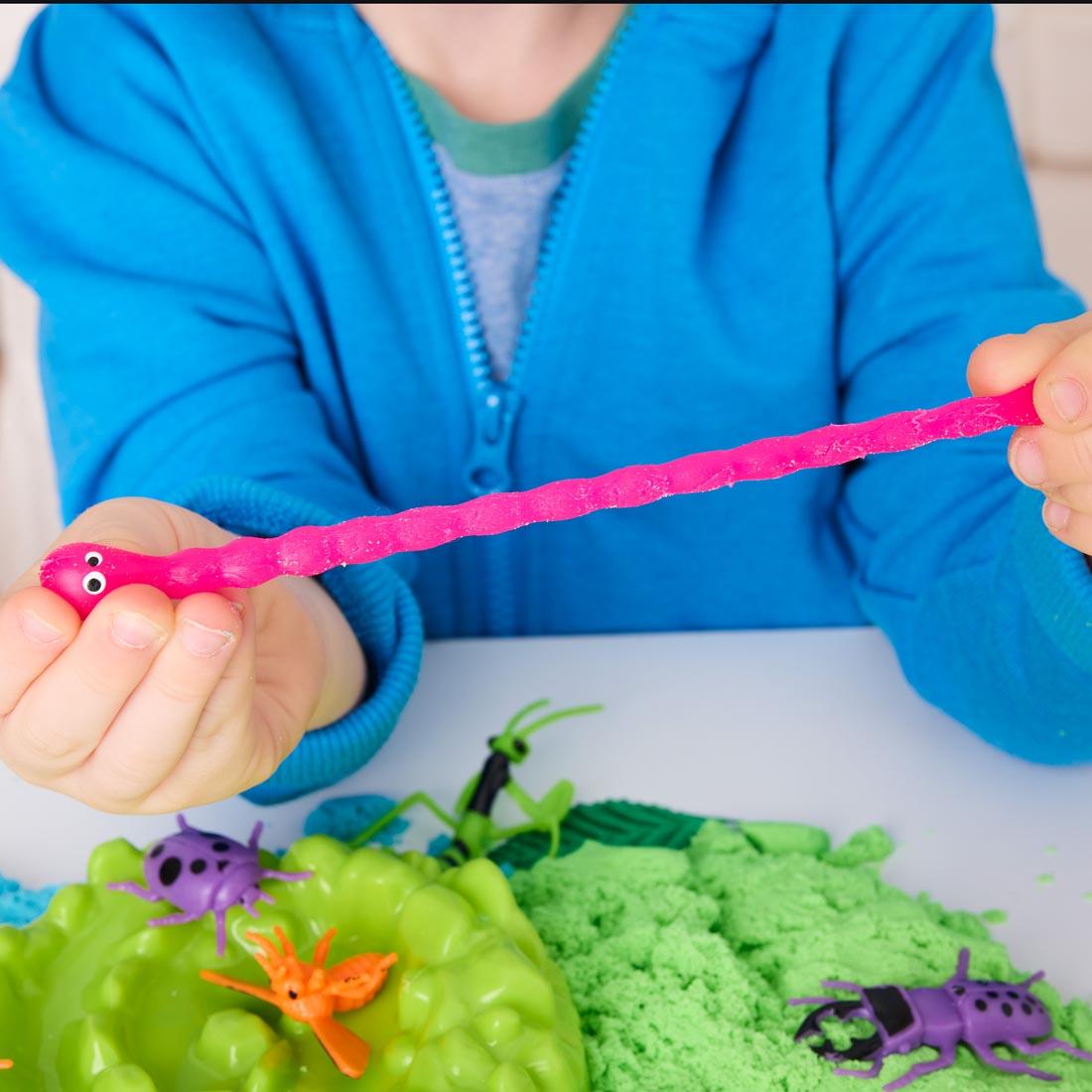 child playing with Neon Bugs Sensory Adventure set, stretching a worm