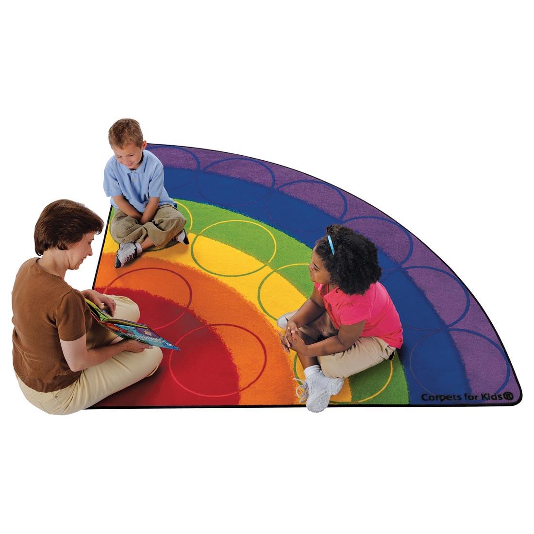 Children and teacher sitting on the Rainbow Row Corner Rug by Carpets For Kids