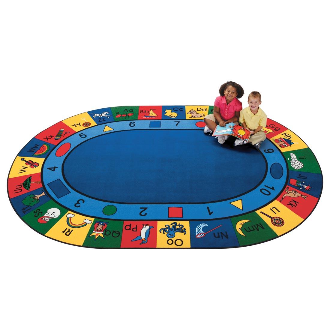 Children sitting with a book on the Blocks of Fun Oval Rug by Carpets For Kids