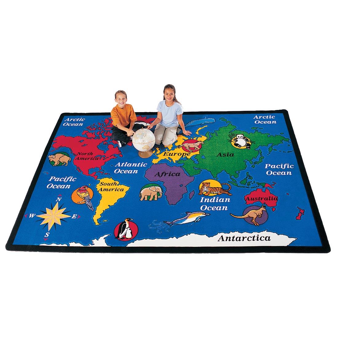 Children with a globe sitting on the World Explorer Rug by Carpets For Kids