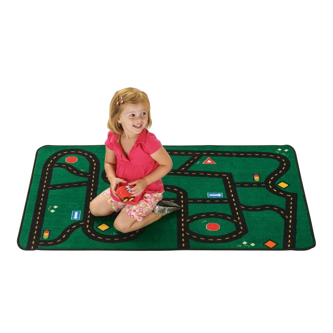 Road Kids Value Rug by Carpets For Kids with a young girl playing on the rug with a toy car
