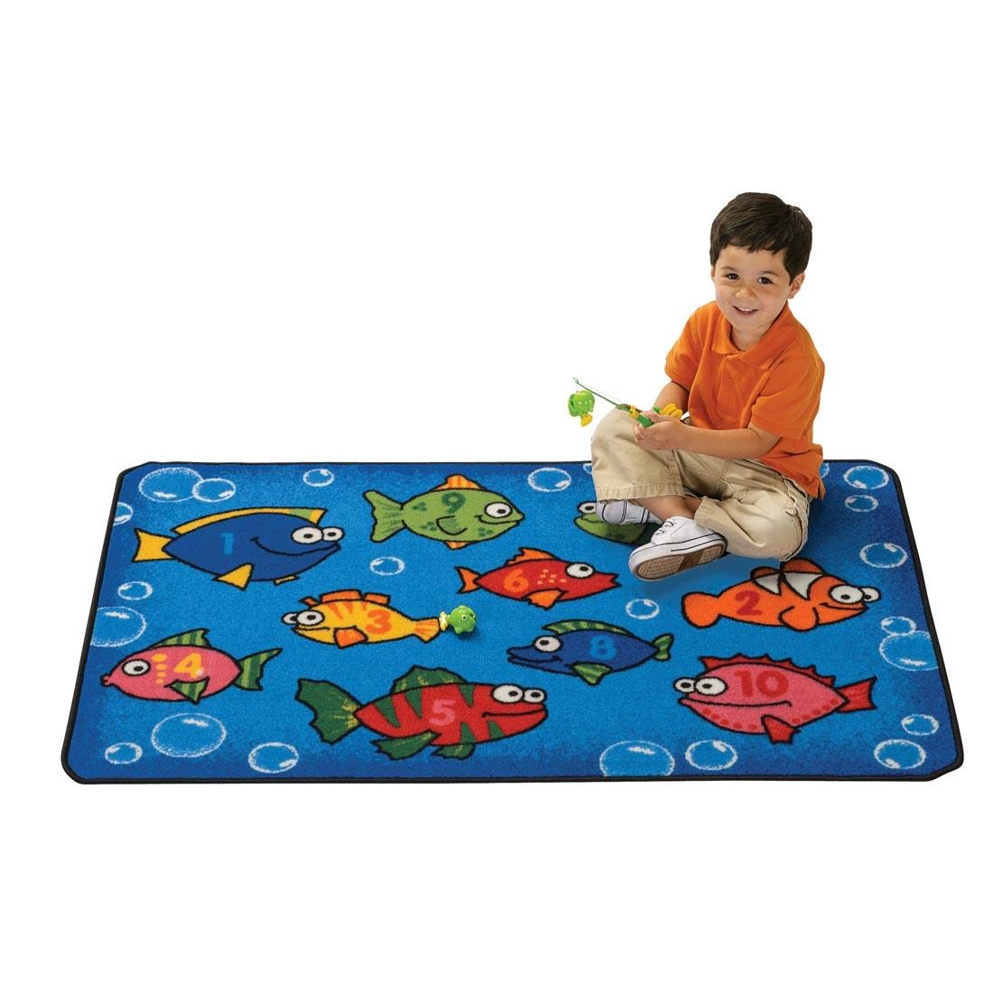 Fish Kids Value Rug by Carpets For Kids with young boy sitting on the rug, holding a toy fishing rod