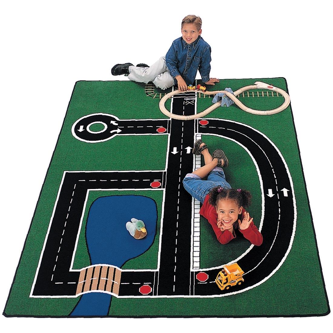 Child sitting and a child laying on the Neighborhood Rug by Carpets For Kids