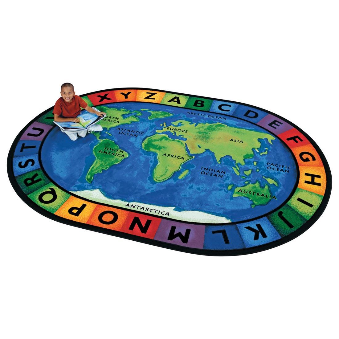 Child with book sitting on the Circletime Around the World Oval Rug by Carpets For Kids