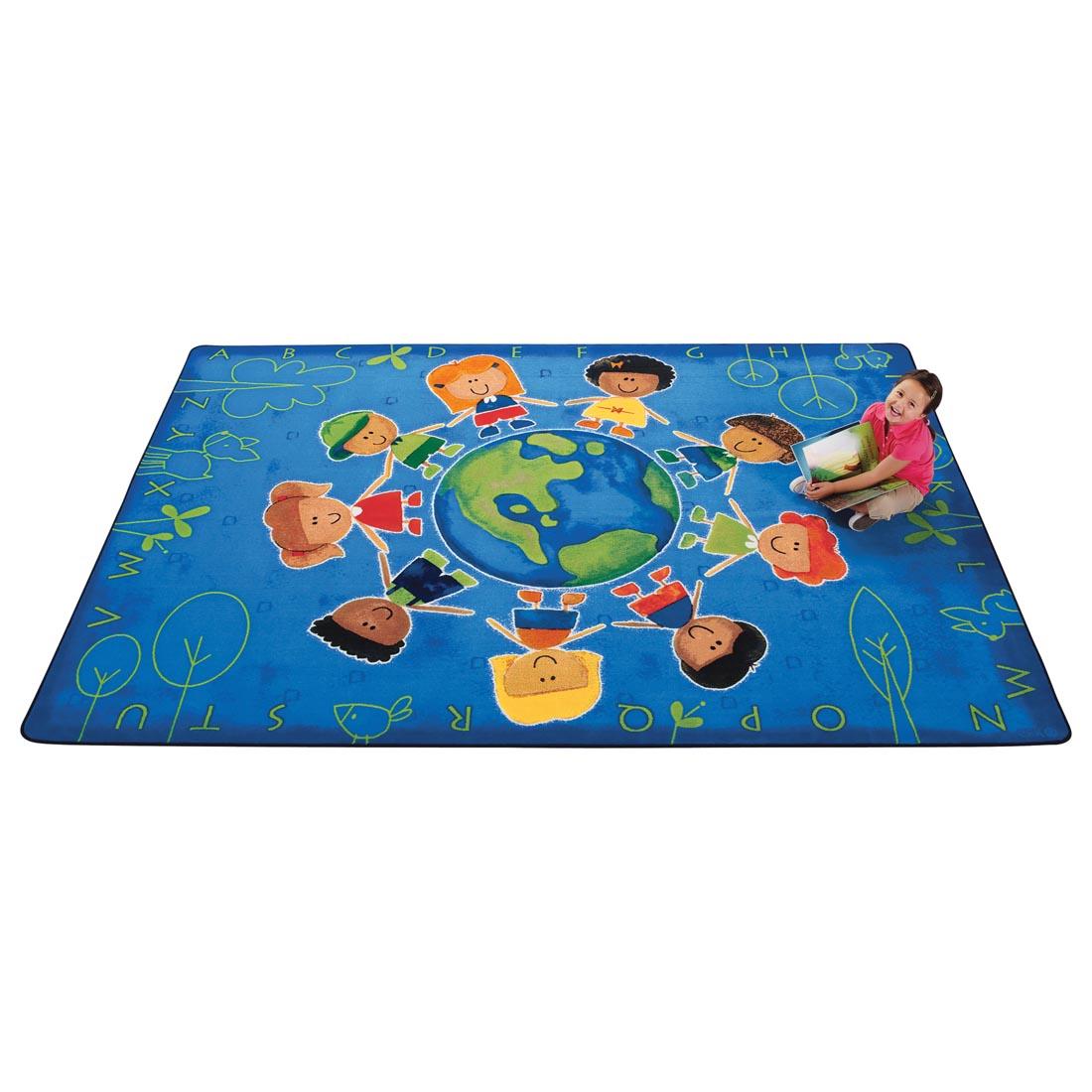 Child with a book sitting on the Give the Planet a Hug Rug by Carpets For Kids