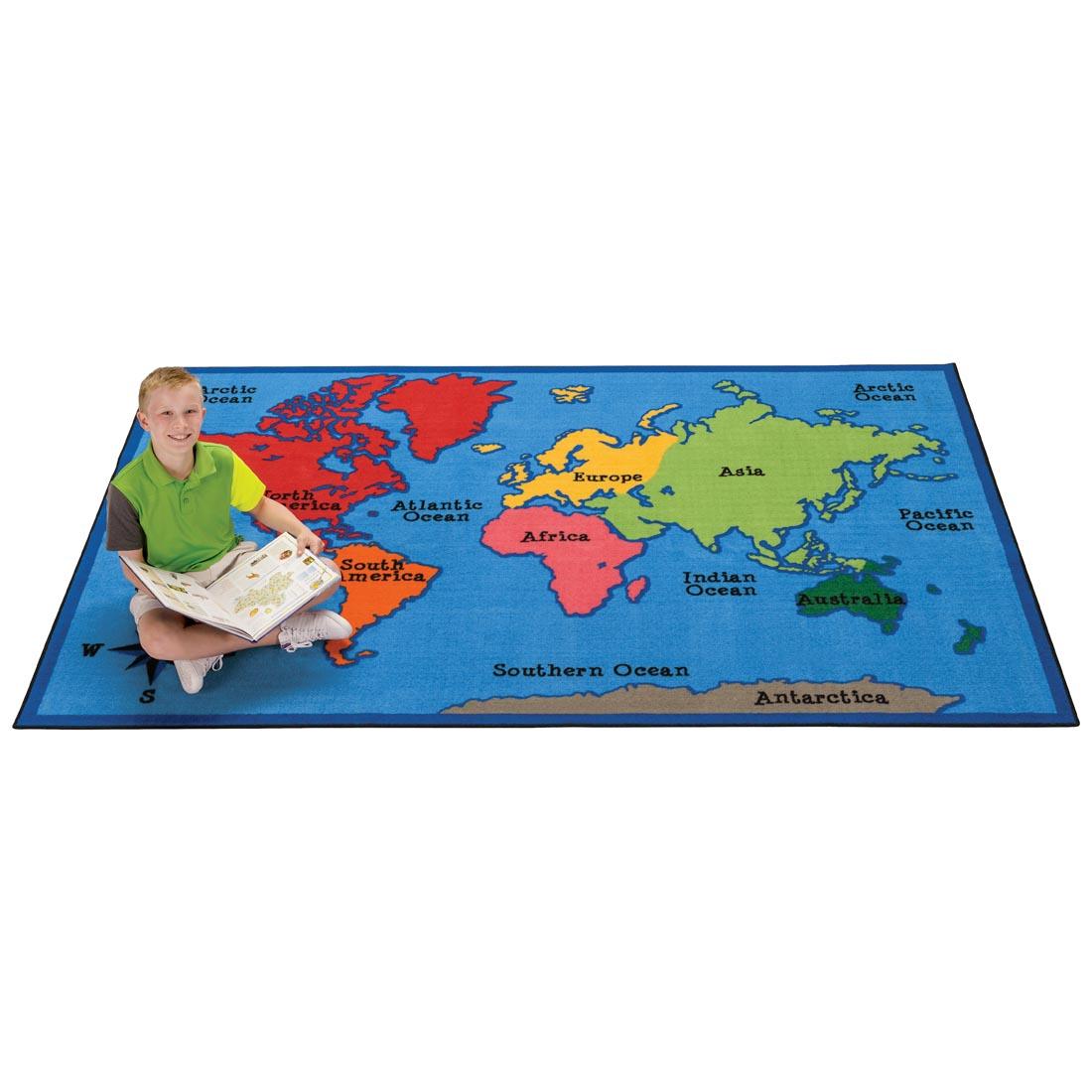 Child with a book sitting on the World Map Kids Value Rug by Carpets For Kids