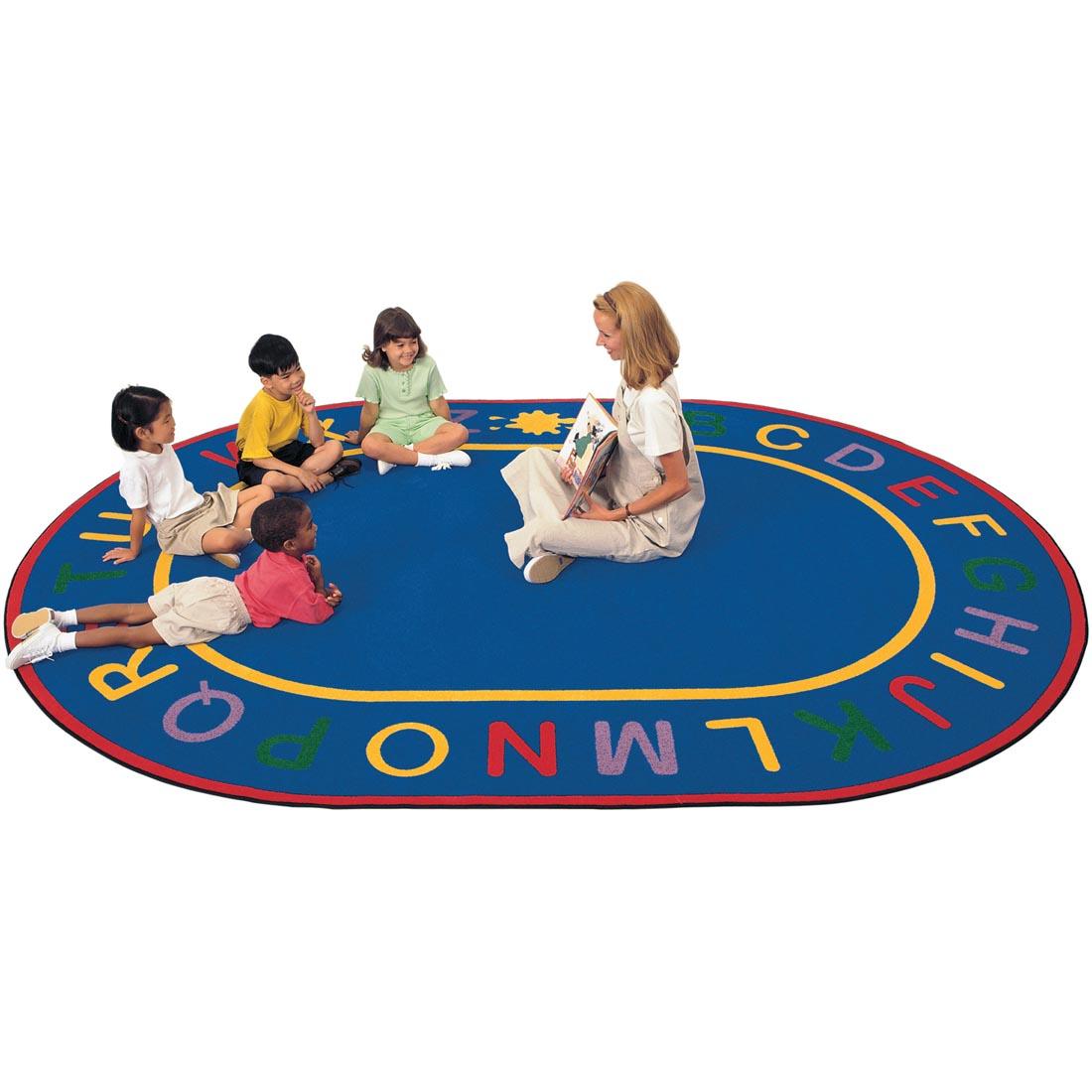 Teacher and students on the Oval Alphabet Rug by Carpets For Kids