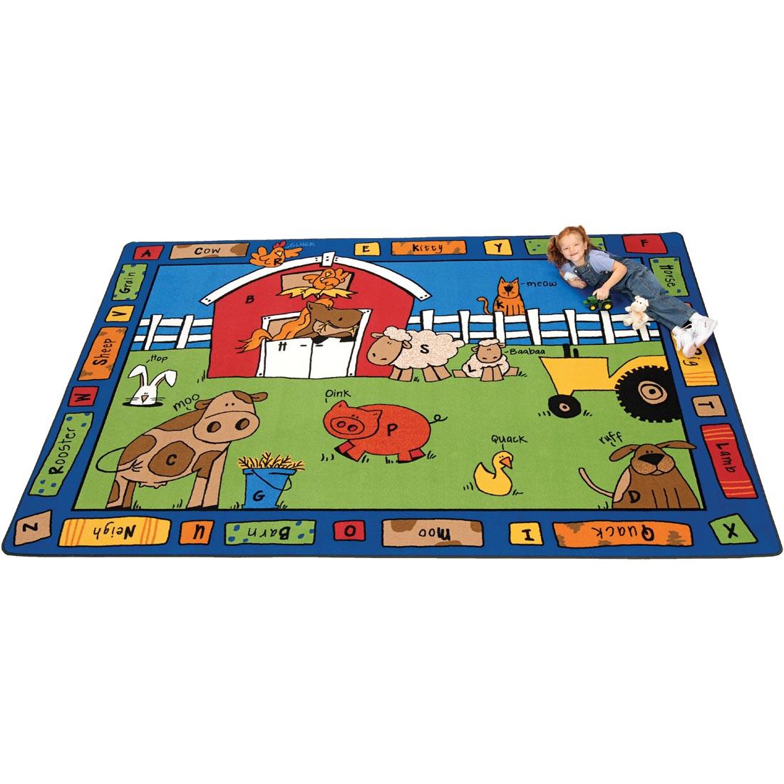Child laying on the Alphabet Farm Rug by Carpets For Kids