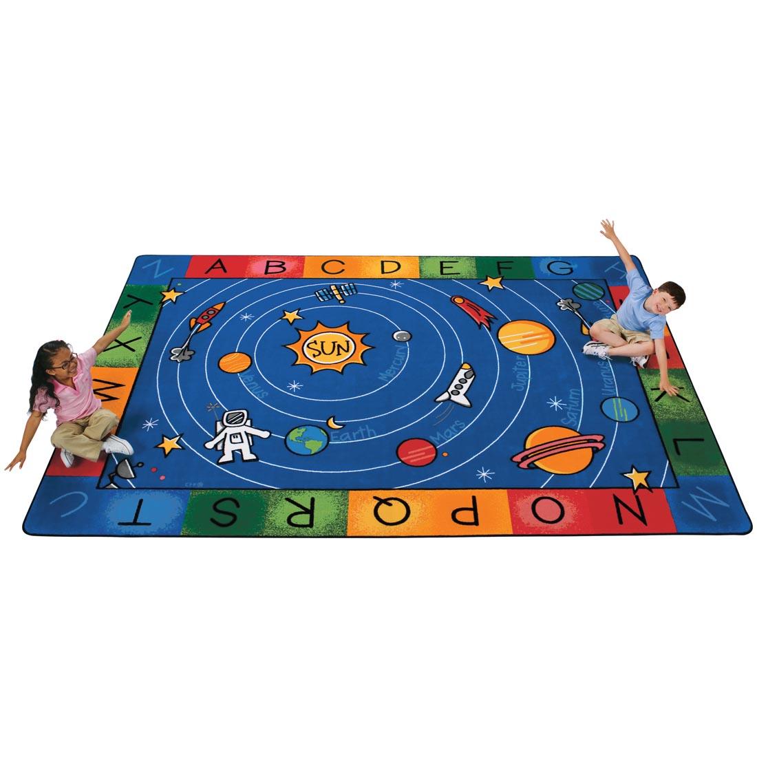 Children sitting on the Outer Space-themed Alphabet Rug by Carpets For Kids