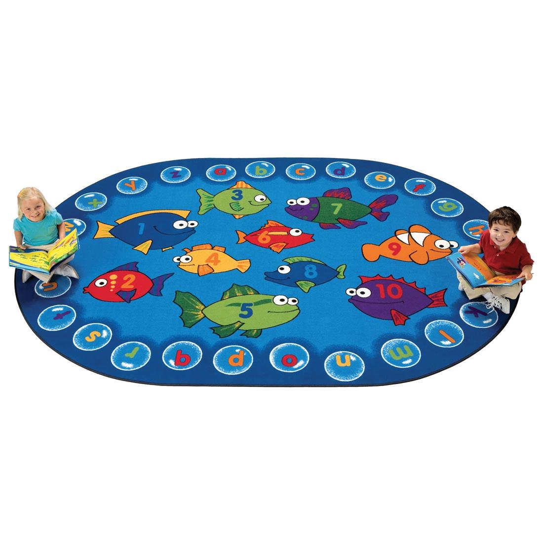 Children with books sitting on the Fishing for Literacy Oval Rug by Carpets For Kids
