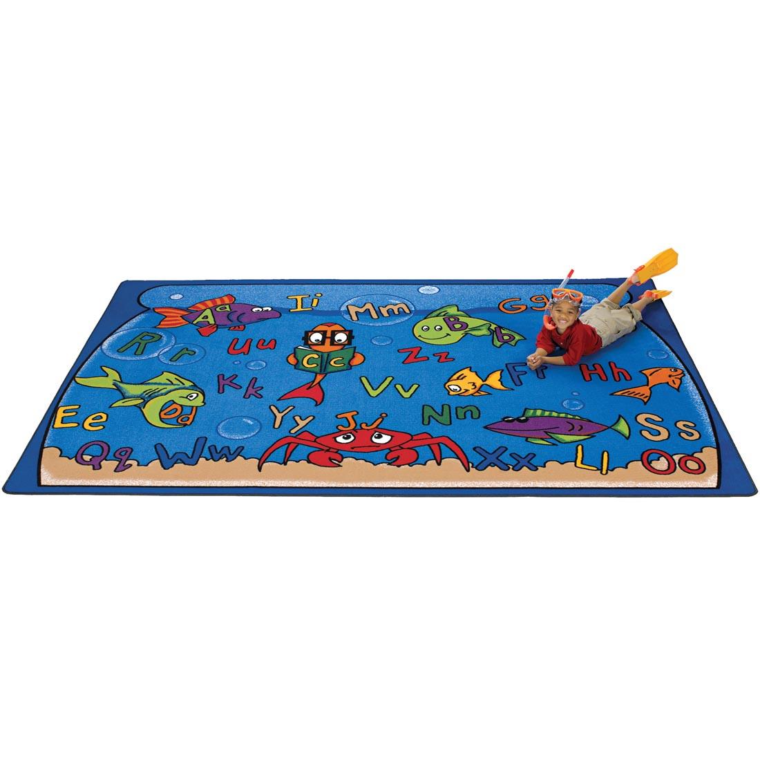 Child wearing snorkeling gear laying on the Alphabet Aquarium Rug by Carpets For Kids