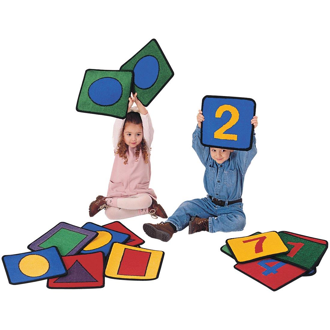 Children holding up the Shape & Number Rug Squares by Carpets For Kids