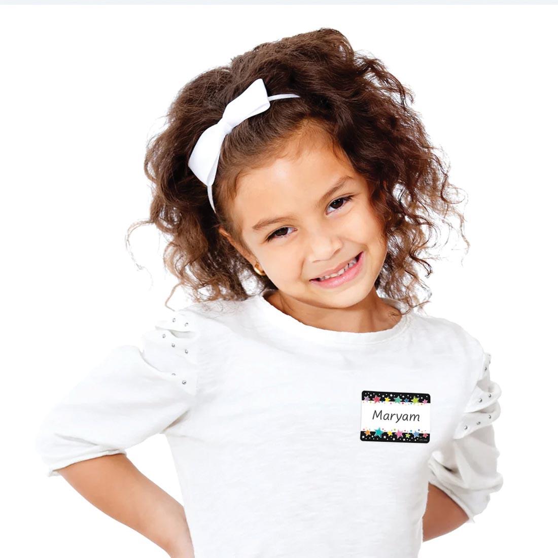 child wearing a name tag made from a Colorful Stars on Black Label from the Star Bright collection By Creative Teaching Press