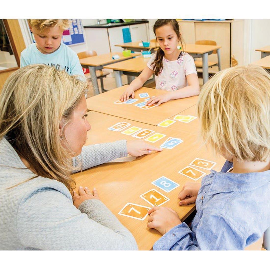 adult showing children how to play Go Figure! Basic Equation Building Card Game By Didax