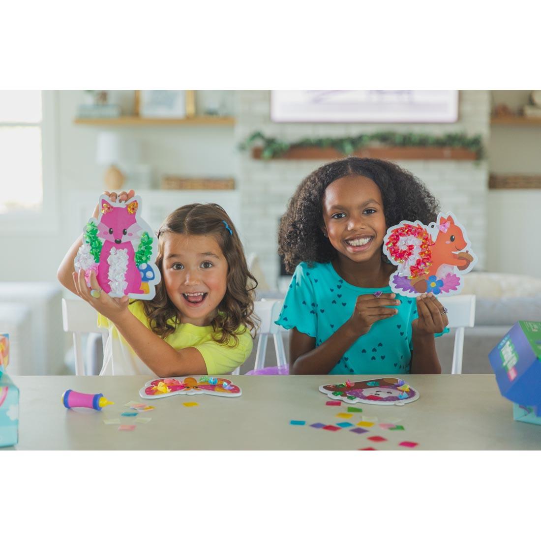 2 kids holding up finished projects from Garden Magic Tufting Kit By Educational Insights