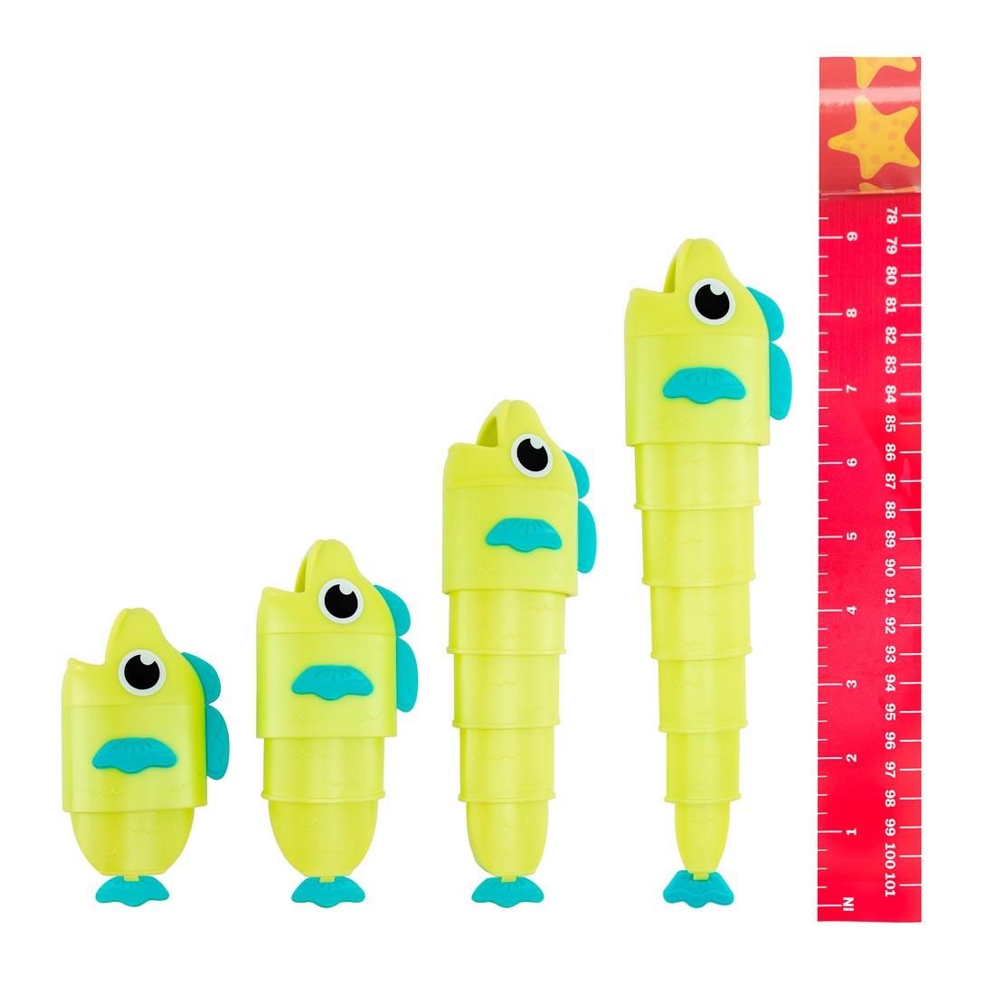 4 toy fish in different lengths with a measuring tape next to the longest fish