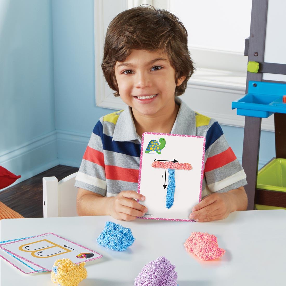 child using playfoam to shape letters onto learning cards