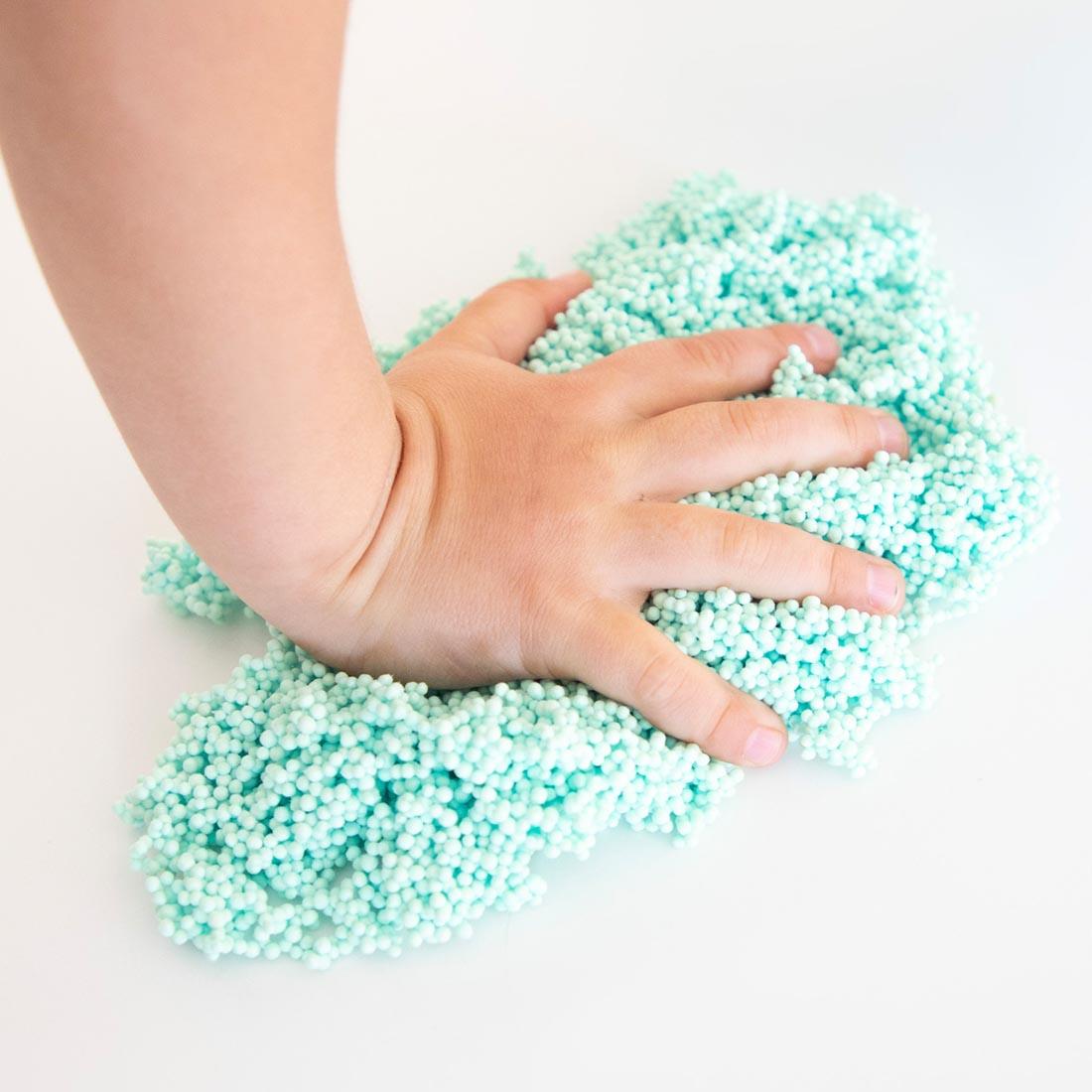 Hand squishing into green Playfoam Modeling Material