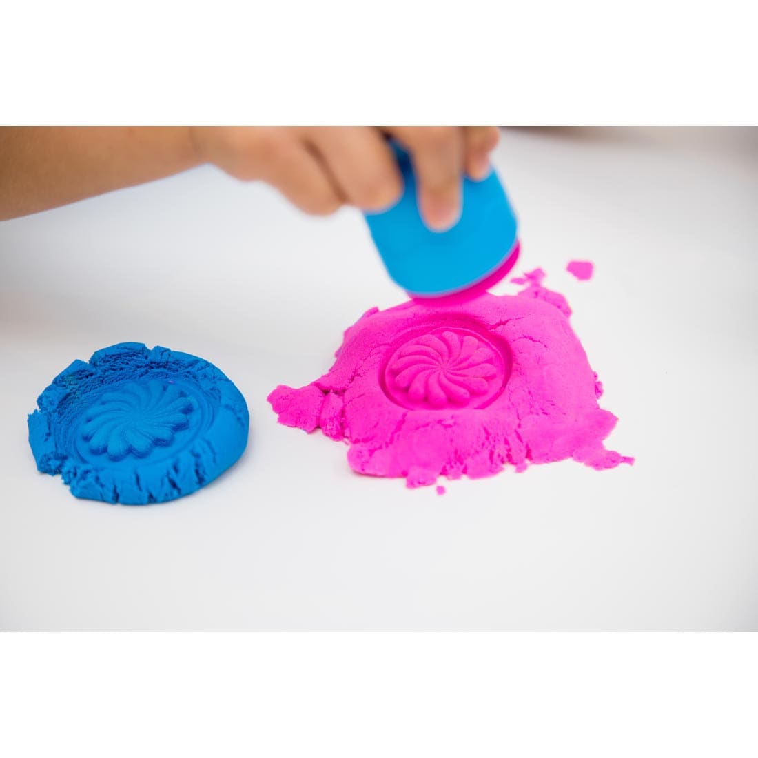 Child making stamp impression in Playfoam sand