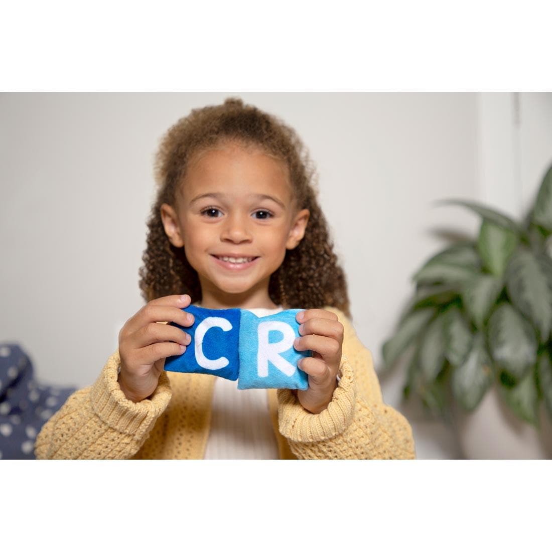 Child holding up letters C and R from Phonics Bean Bags set By Educational Insights