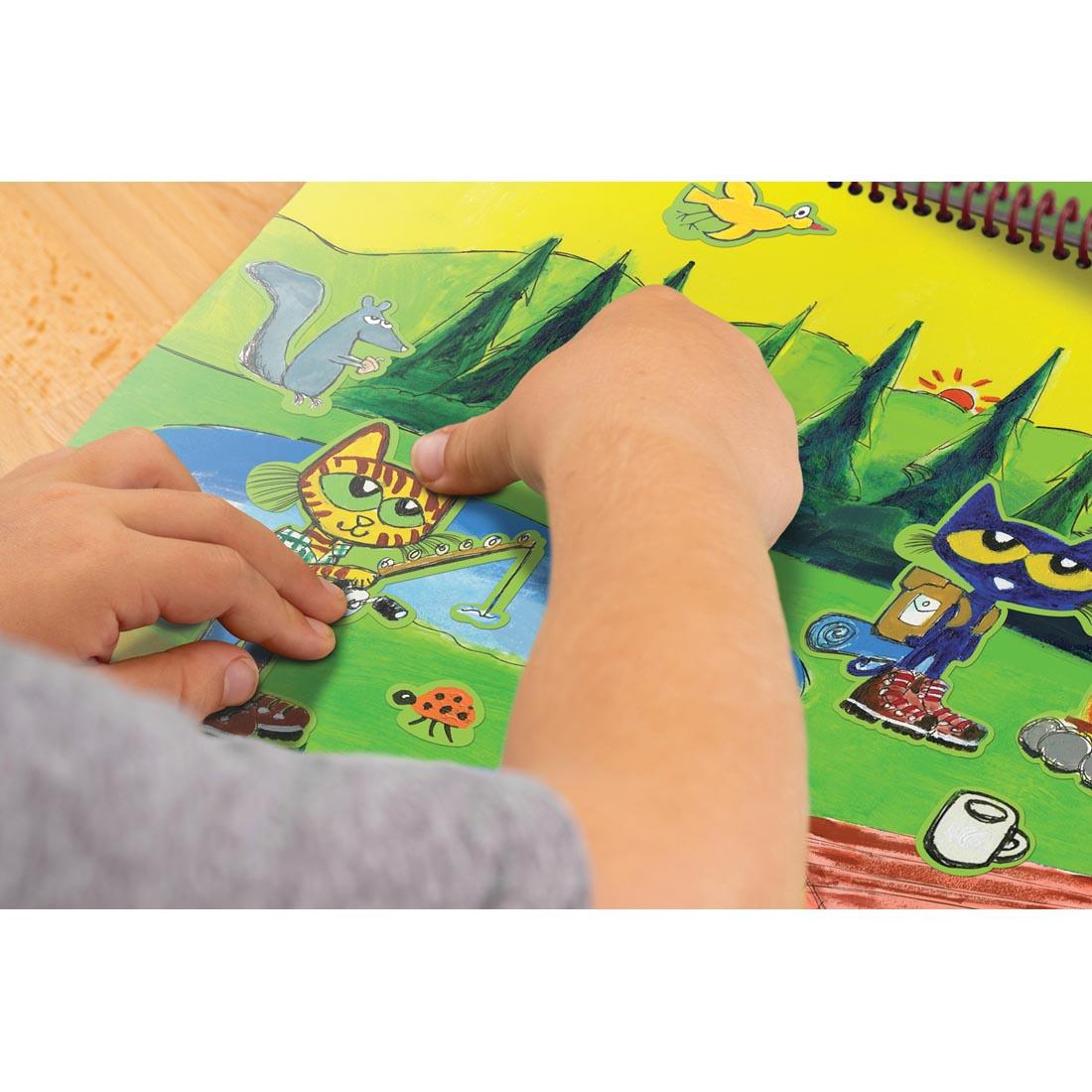 Child's hands placing a sticker on the Pete the Cat Reusable Sticker Pad