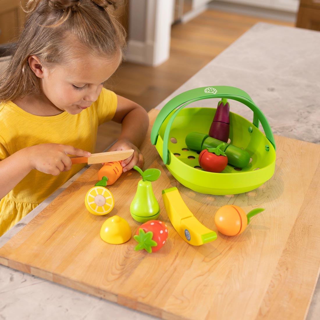 child slicing play food from the Pretendables Fruit & Veggie Basket set