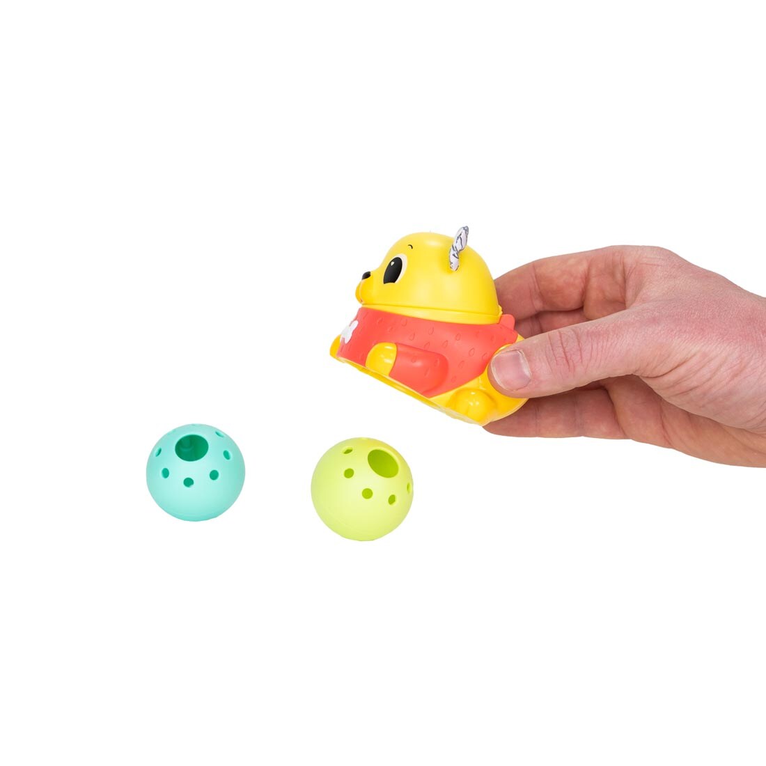 hand holding the Crawl & Chase Pug Popper By Lamaze over two balls