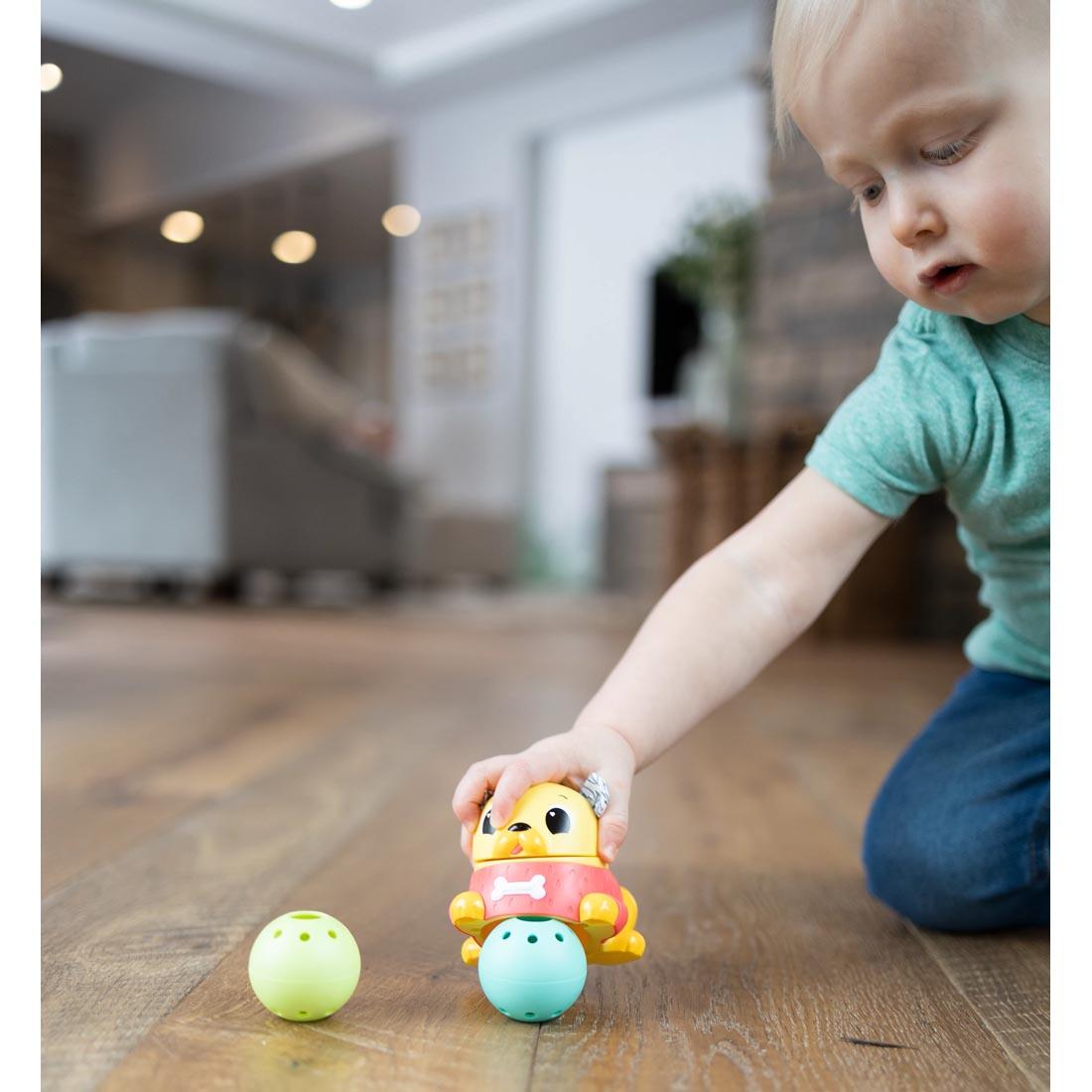 child on the floor playing with the Crawl & Chase Pug Popper By Lamaze