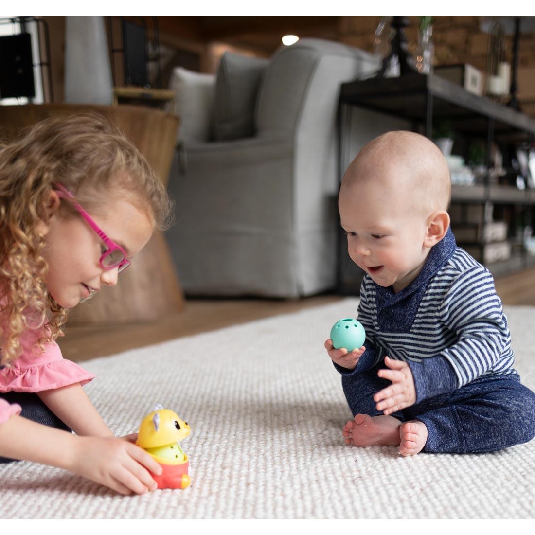 2 children on the floor playing with the Crawl & Chase Pug Popper By Lamaze