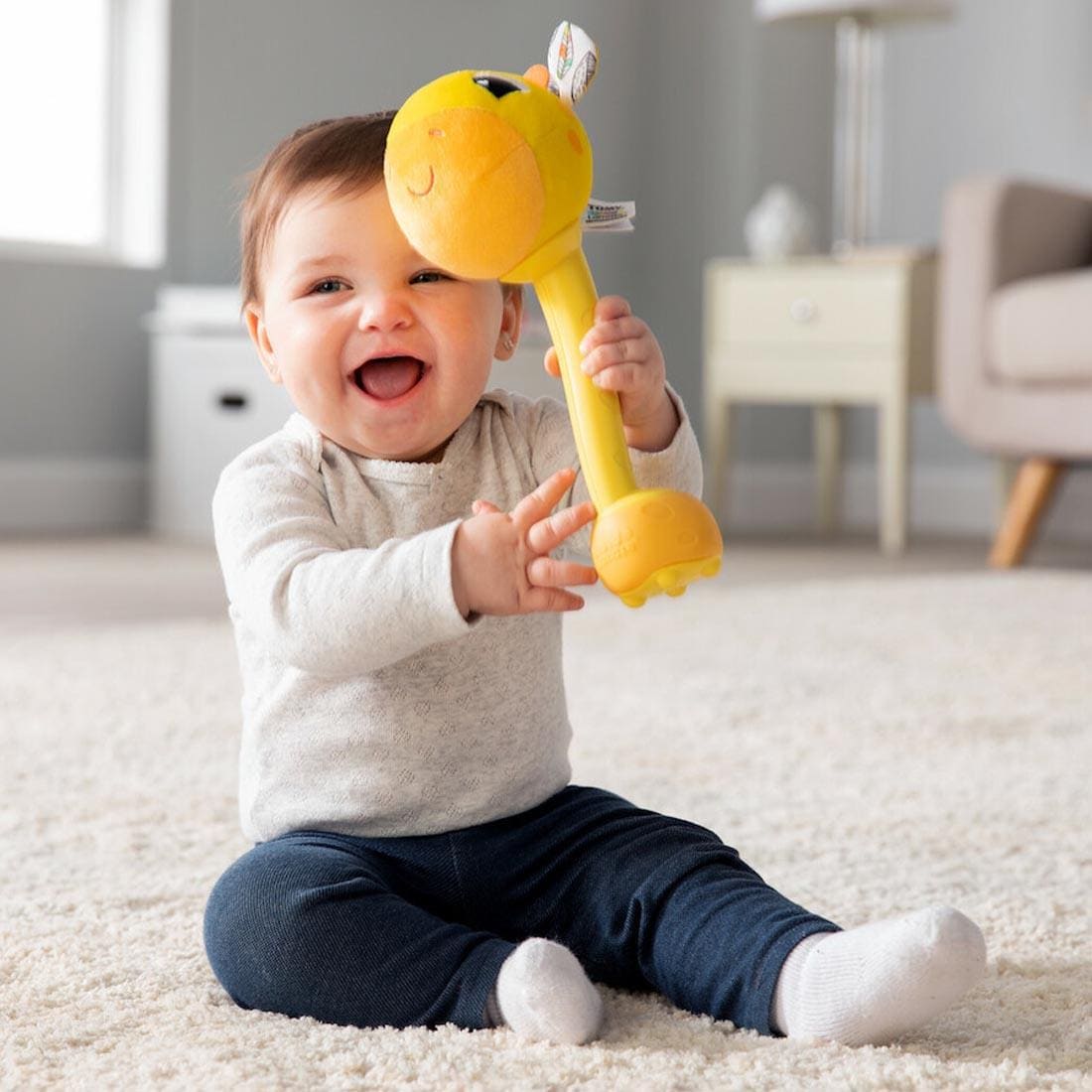 baby sitting on the floor with a Wacky Giraffe By Lamaze in their hands