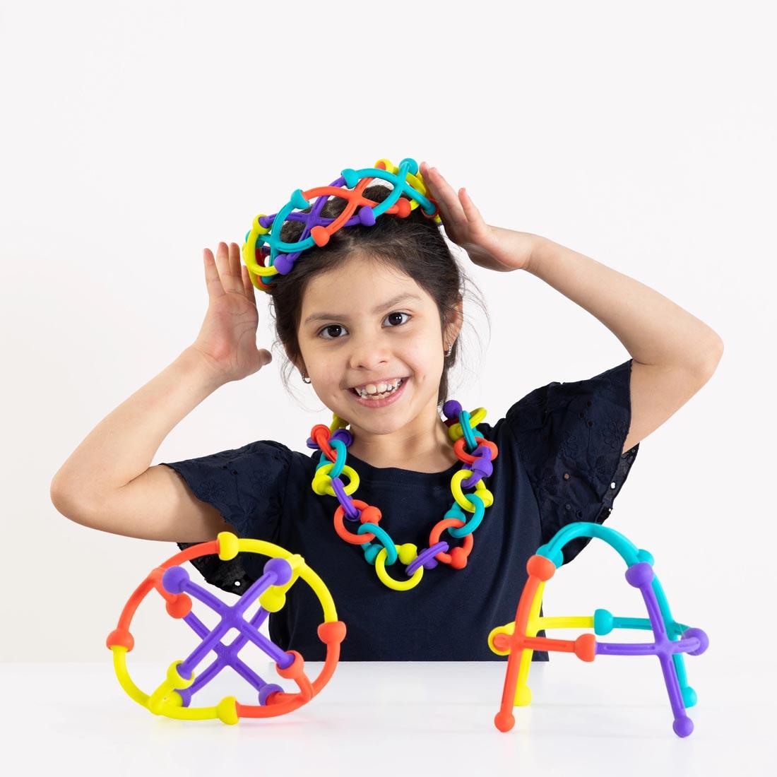 child wearing crown and necklace with two more creations in front; all made with pieces from the Plip Kit
