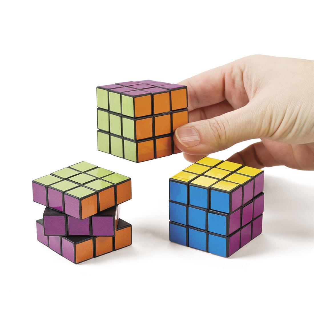 three Mini Bright Magic Cubes by Fun Express; a hand is holding one of them