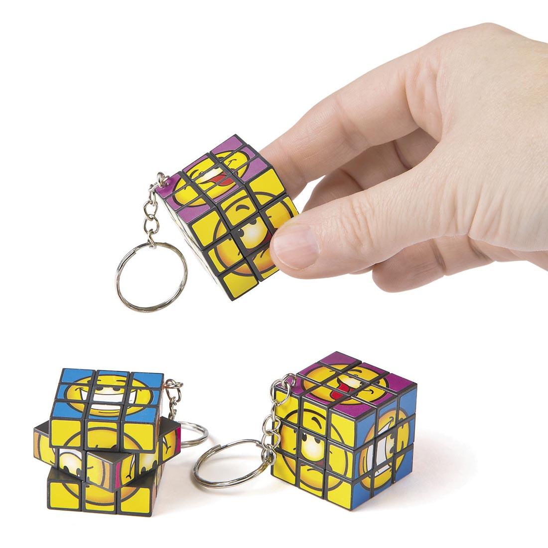 three Mini Magic Cube Puzzle Key Chains by Fun Express with a hand holding one of them